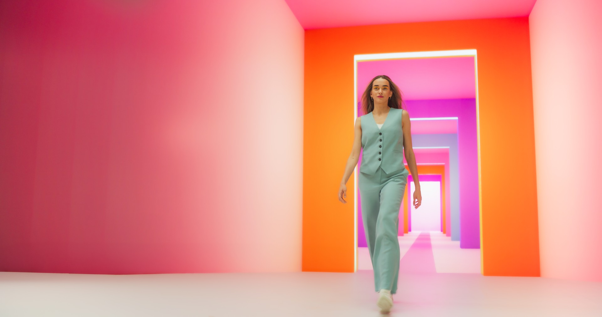 Portrait en contre-plongée d’une jeune femme à la mode effectuant un défilé dans un studio de néon coloré. Femme élégante marchant en toute confiance dans une pièce éclairée par la lumière, travaillant comme modèle pour une marque de mode lu